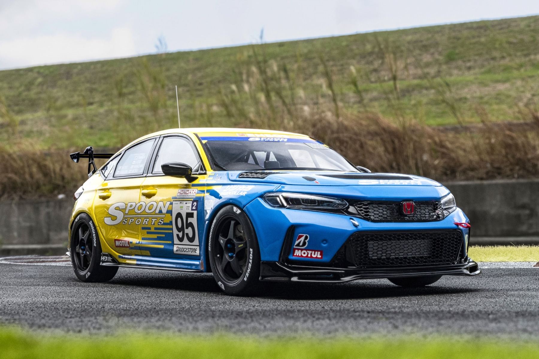 サーキットでも映えるブルーとイエローのボディカラーはSPOON伝統のカラーリングです。リップスポイラーはオリジナルパーツで、バンパーの右側にはエアジャッキのチャック、左側にはトーイングフックを装備。