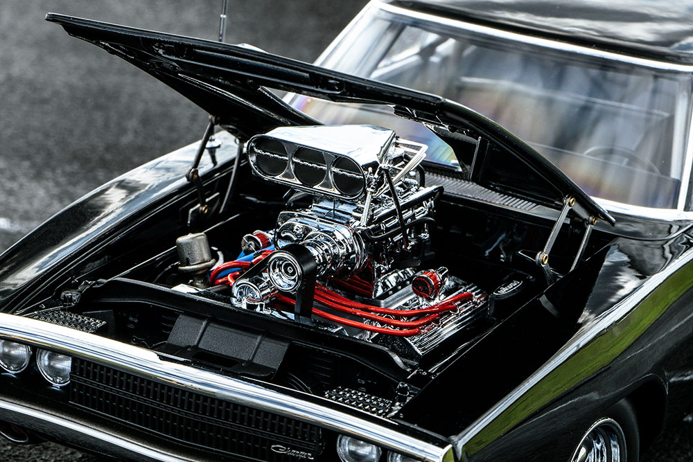 Lift the massive hood to see the hallmark of American muscle, the V8 engine. The chrome-finished engine bay is a sight to behold, with red plug wires and blue hoses adding striking accents that elevate the whole setup.